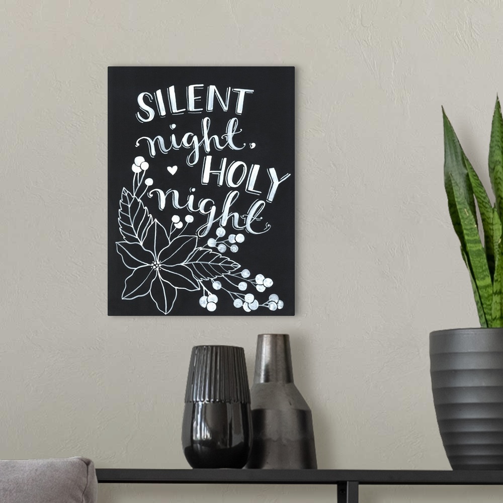 A modern room featuring The words "Silent night, holy night" handwritten on a dark background with a large poinsettia flo...