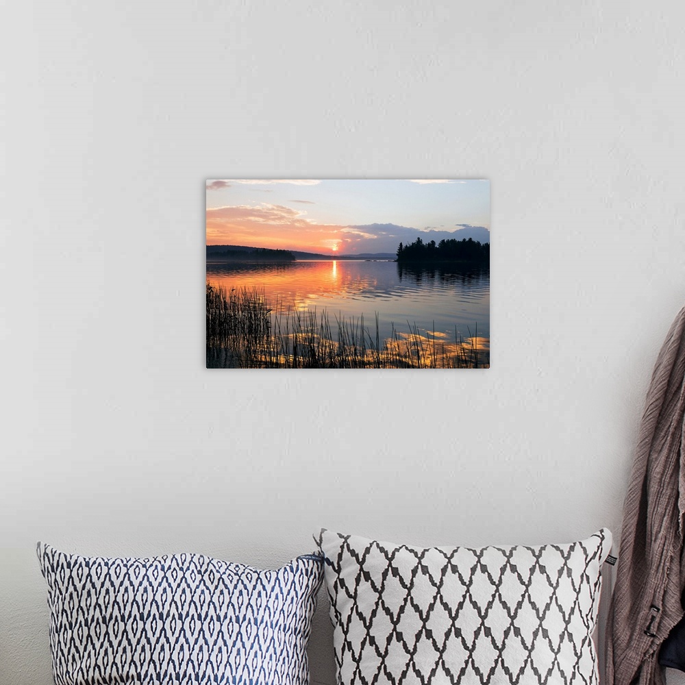 A bohemian room featuring Canvas print of a peaceful lake with a sunset reflected onto it.