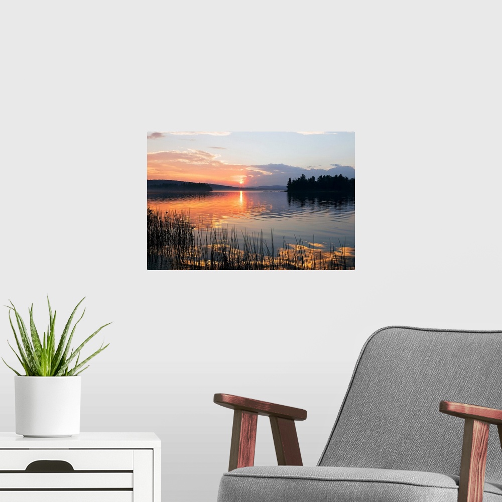 A modern room featuring Canvas print of a peaceful lake with a sunset reflected onto it.