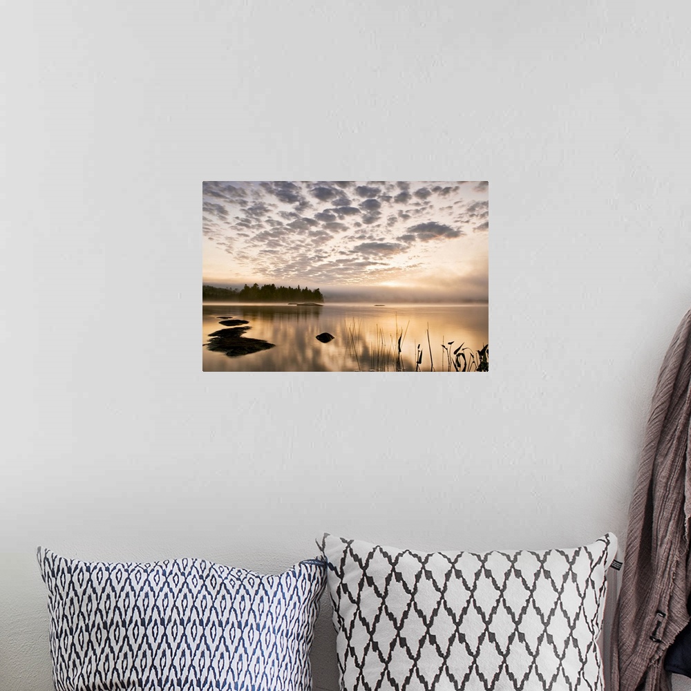 A bohemian room featuring Horizontal photograph on a big wall hanging of the sun set reflecting in a large body of water, a...