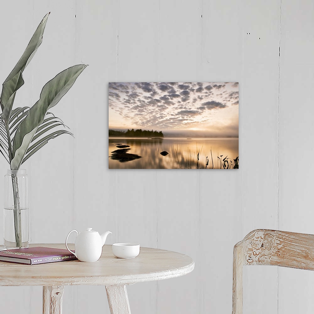 A farmhouse room featuring Horizontal photograph on a big wall hanging of the sun set reflecting in a large body of water, a...