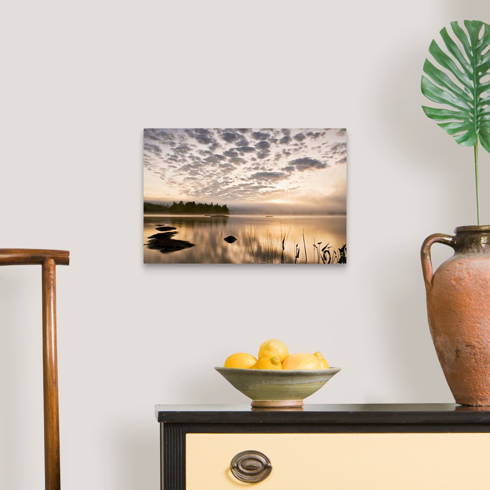 A traditional room featuring Horizontal photograph on a big wall hanging of the sun set reflecting in a large body of water, a...