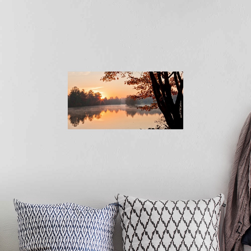 A bohemian room featuring Big Canvas photo of a tranquil lake at sunrise with forests around it bathed in warm sunlight.