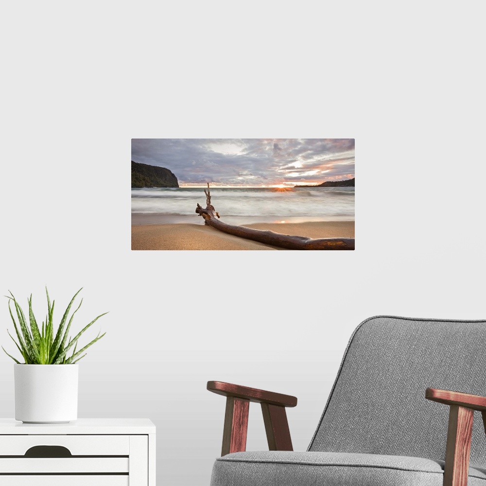 A modern room featuring This landscape canvas is a sandy beach at sunset sheltered with steep rock faces; the composition...
