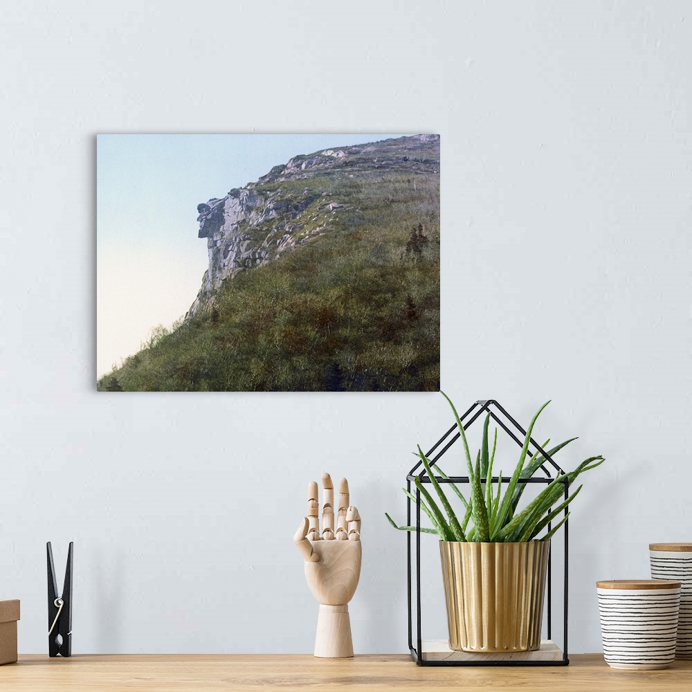 A bohemian room featuring Photo on canvas of the face of a man made out of rocks hanging on a cliff of a mountain.