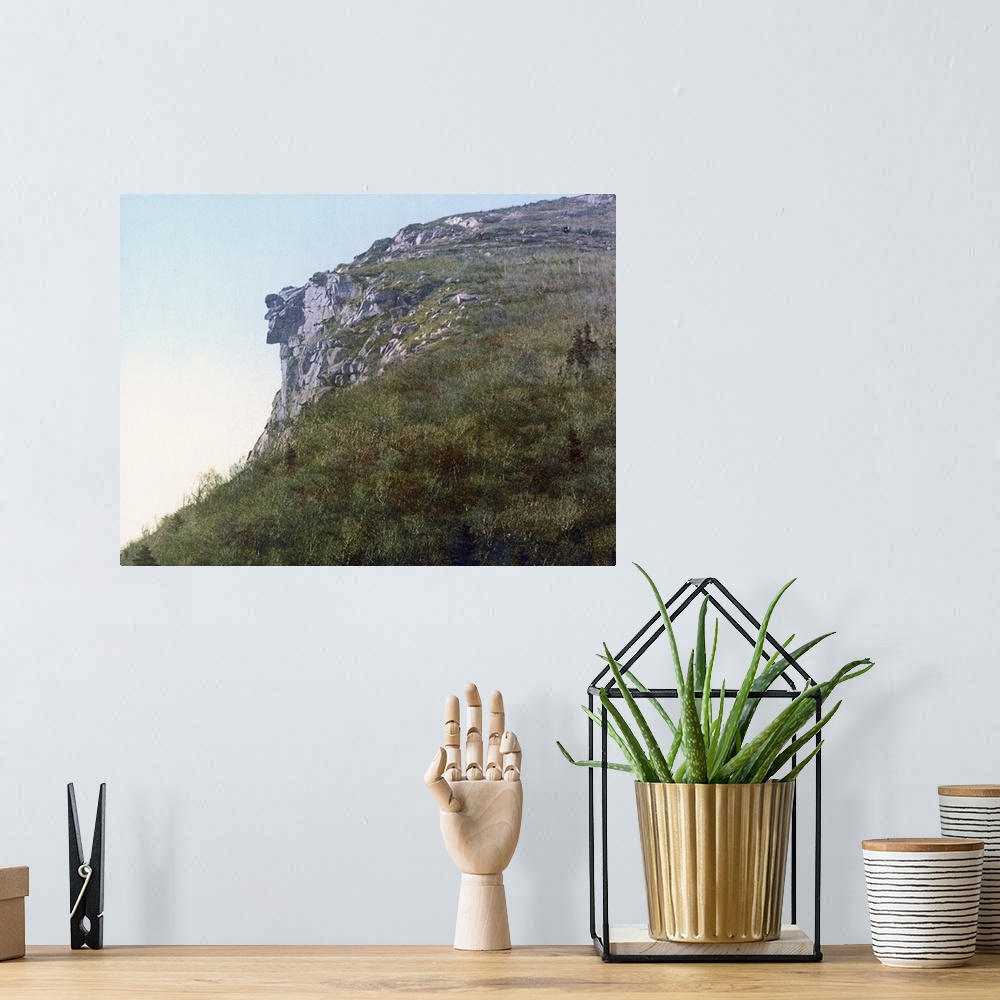 A bohemian room featuring Photo on canvas of the face of a man made out of rocks hanging on a cliff of a mountain.