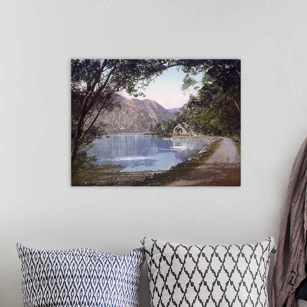 A bohemian room featuring A vintage shot of a gravel path winding its way at the water's edge as leafy trees and cliffs loo...