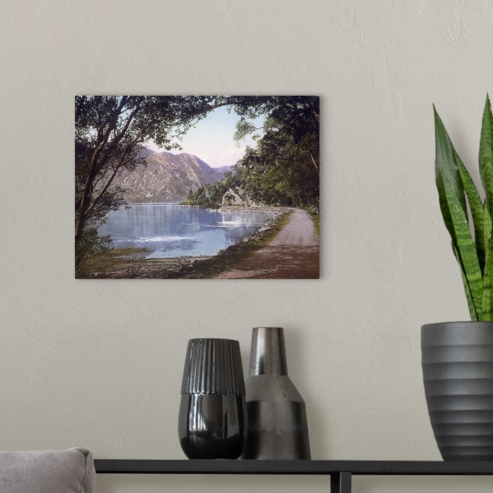 A modern room featuring A vintage shot of a gravel path winding its way at the water's edge as leafy trees and cliffs loo...