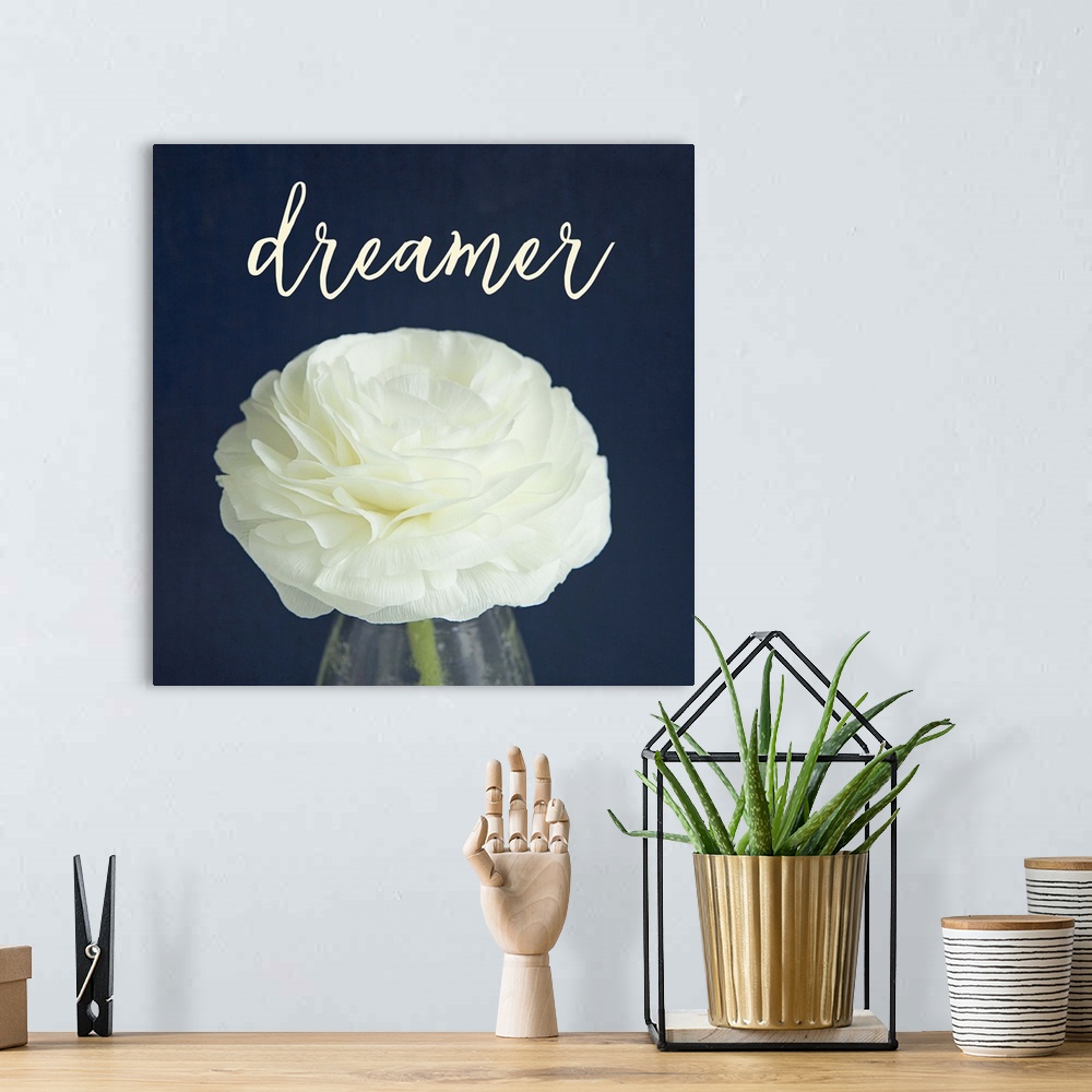 A bohemian room featuring A white flower in a glass vase with the word "dreamer" above it.