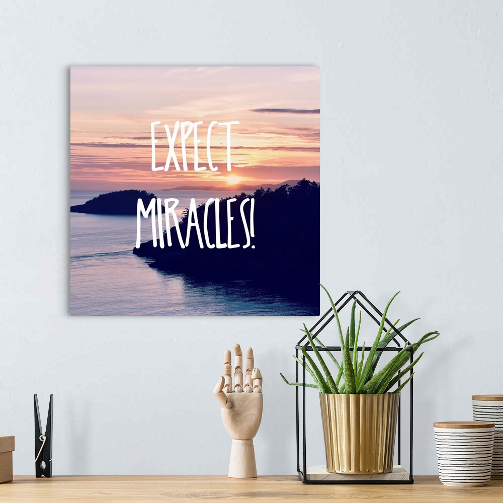 A bohemian room featuring "Expect Miracles!" written in white on top of a square photograph of a beautiful sunset over water.
