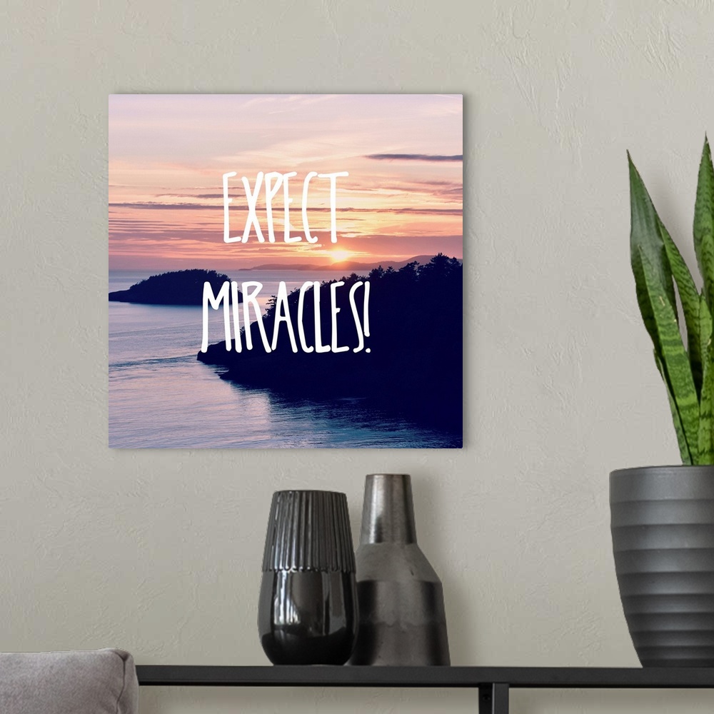 A modern room featuring "Expect Miracles!" written in white on top of a square photograph of a beautiful sunset over water.