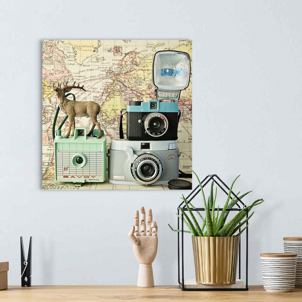 A bohemian room featuring A toy deer on a set of three vintage cameras with a map backdrop.