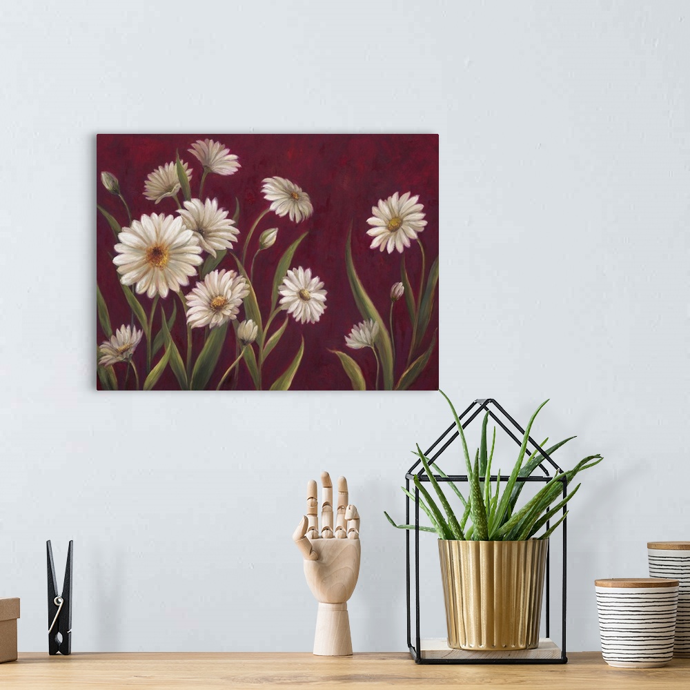 A bohemian room featuring Home decor artwork of white daisies against a deep red background.