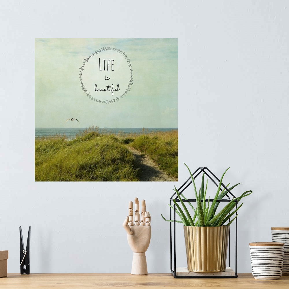 A bohemian room featuring "Life Is Beautiful" written inside a leafy circle on top of a square photograph of a grassy dune ...