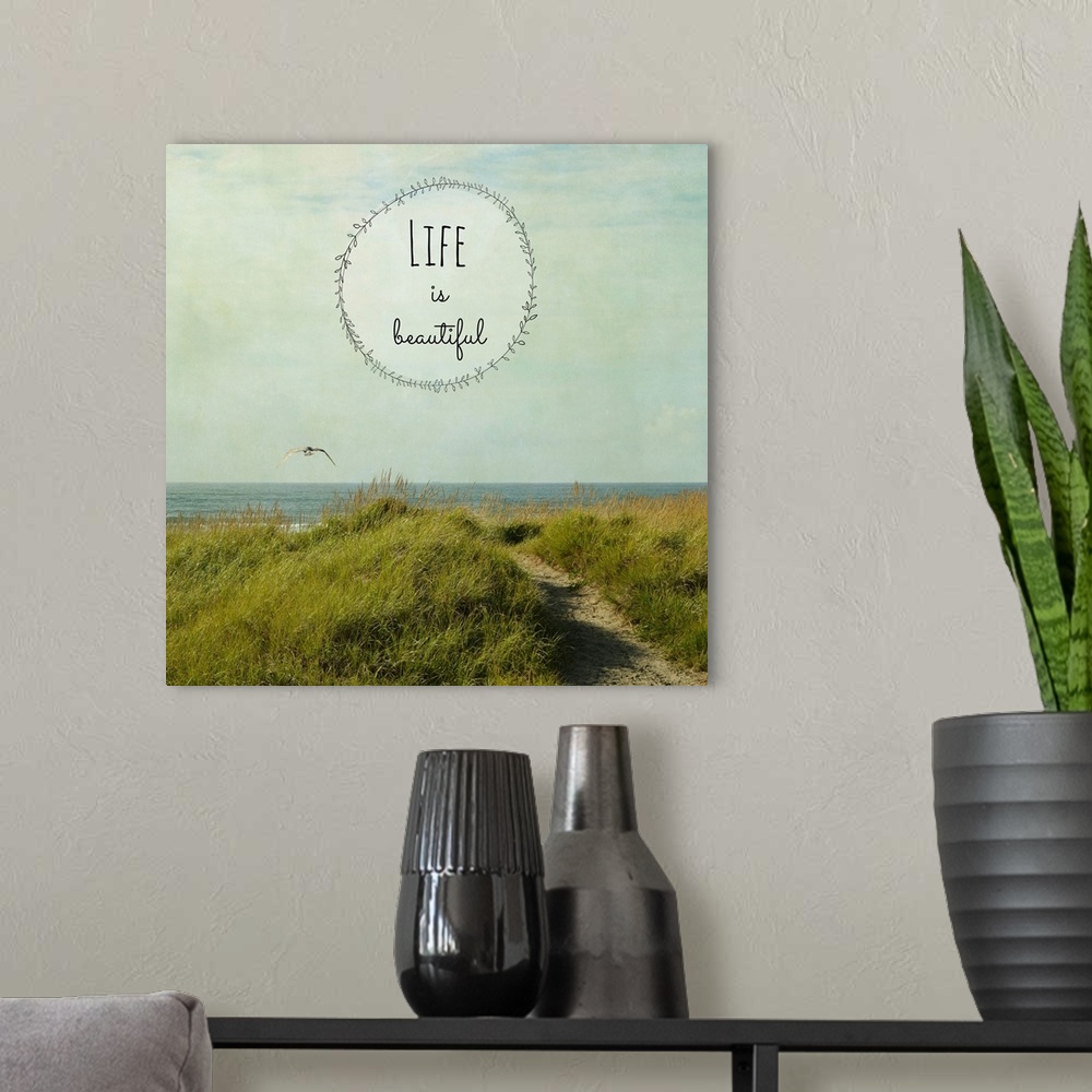 A modern room featuring "Life Is Beautiful" written inside a leafy circle on top of a square photograph of a grassy dune ...