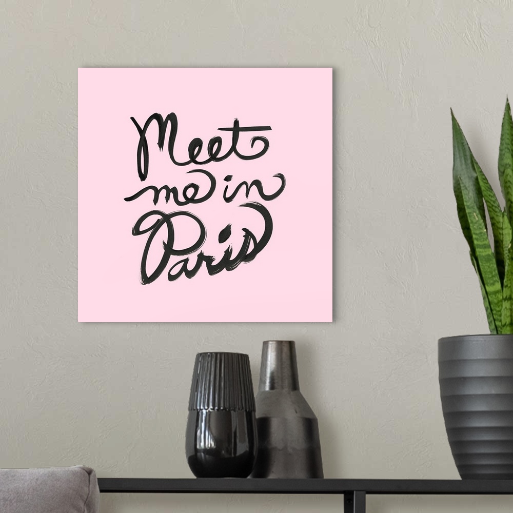 A modern room featuring "Meet Me In Paris" hand lettered in black on a pastel pink background.