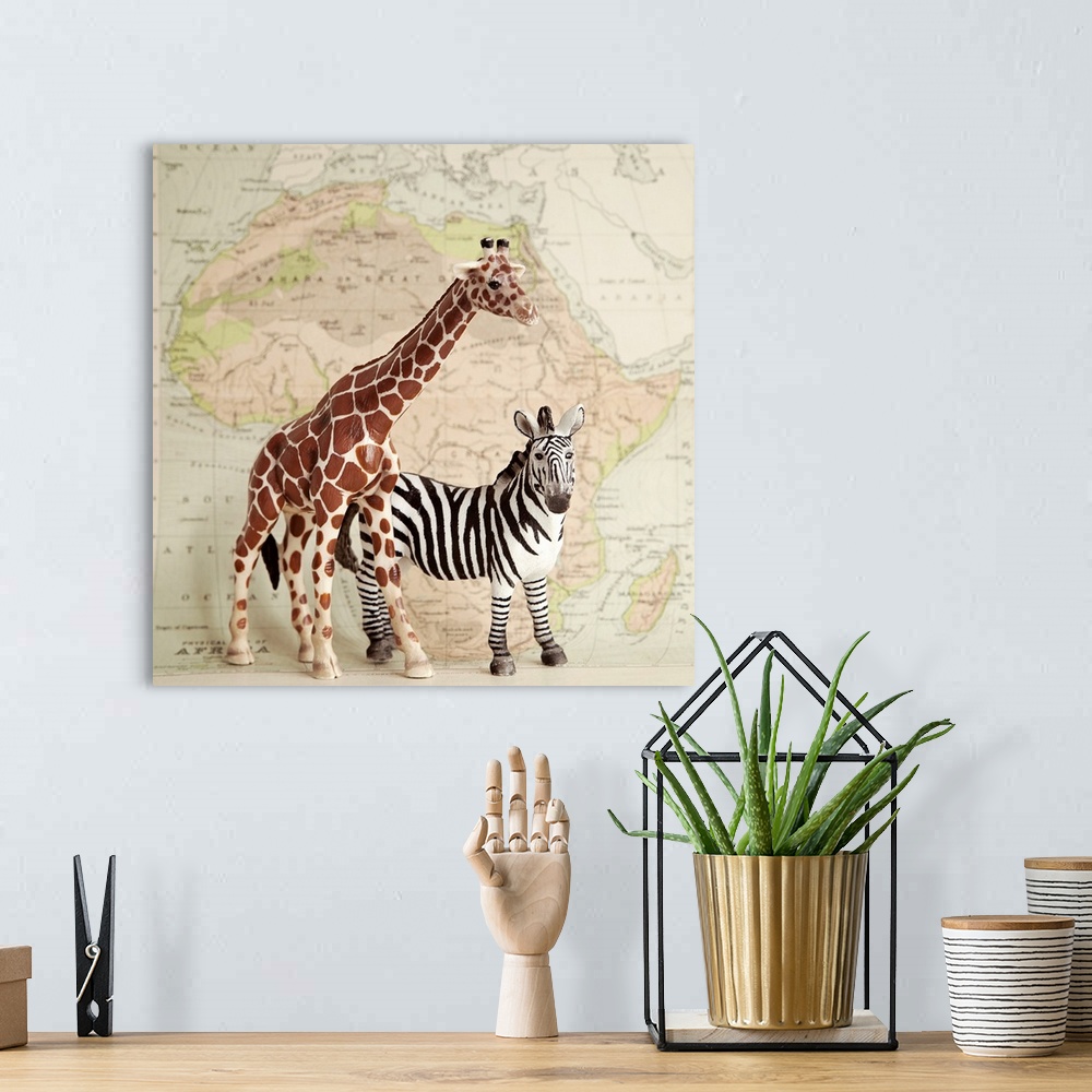 A bohemian room featuring A toy giraffe and zebra with a vintage map backdrop.