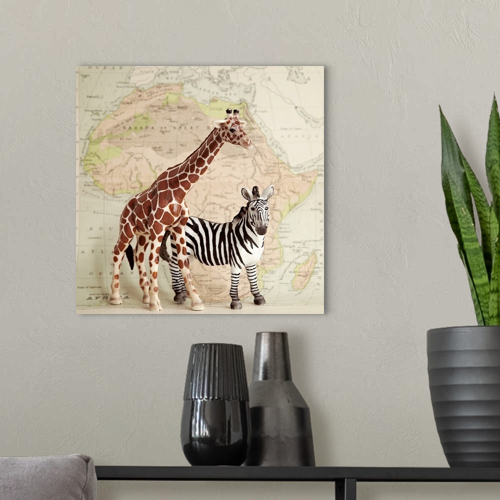 A modern room featuring A toy giraffe and zebra with a vintage map backdrop.