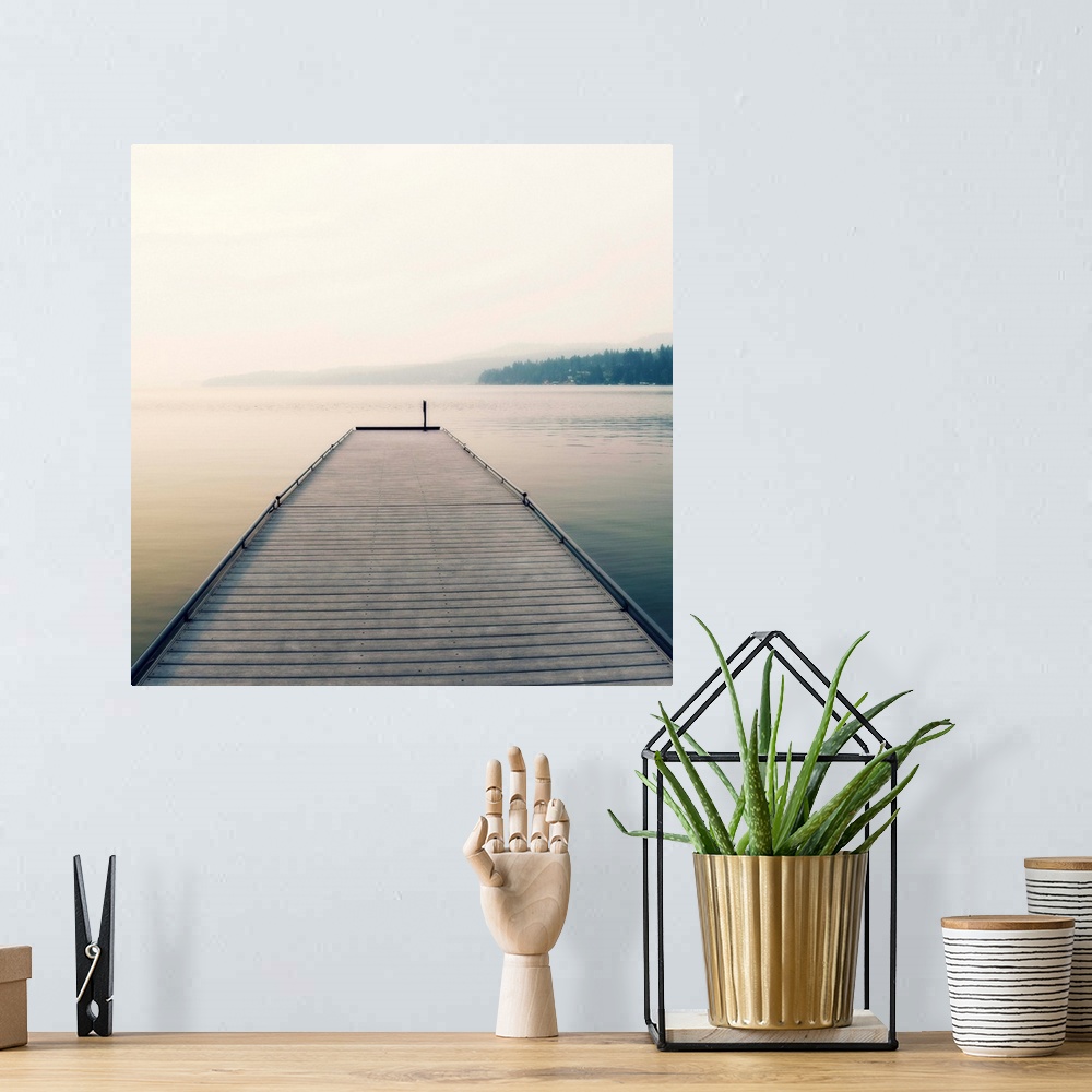 A bohemian room featuring Square photograph of a wooden pier leading out the the middle of a foggy lake.