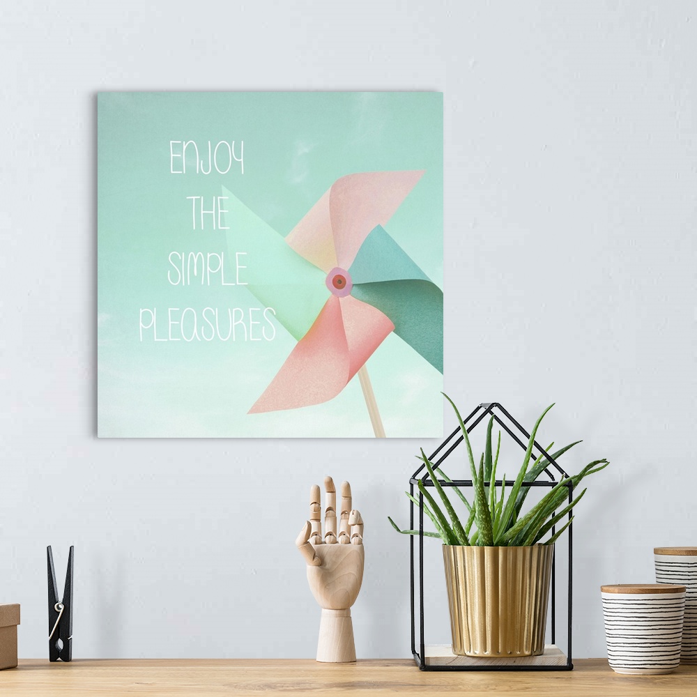 A bohemian room featuring "Enjoy The Simple Pleasures" written on top of a square illustration of a pastel colored pinwheel.