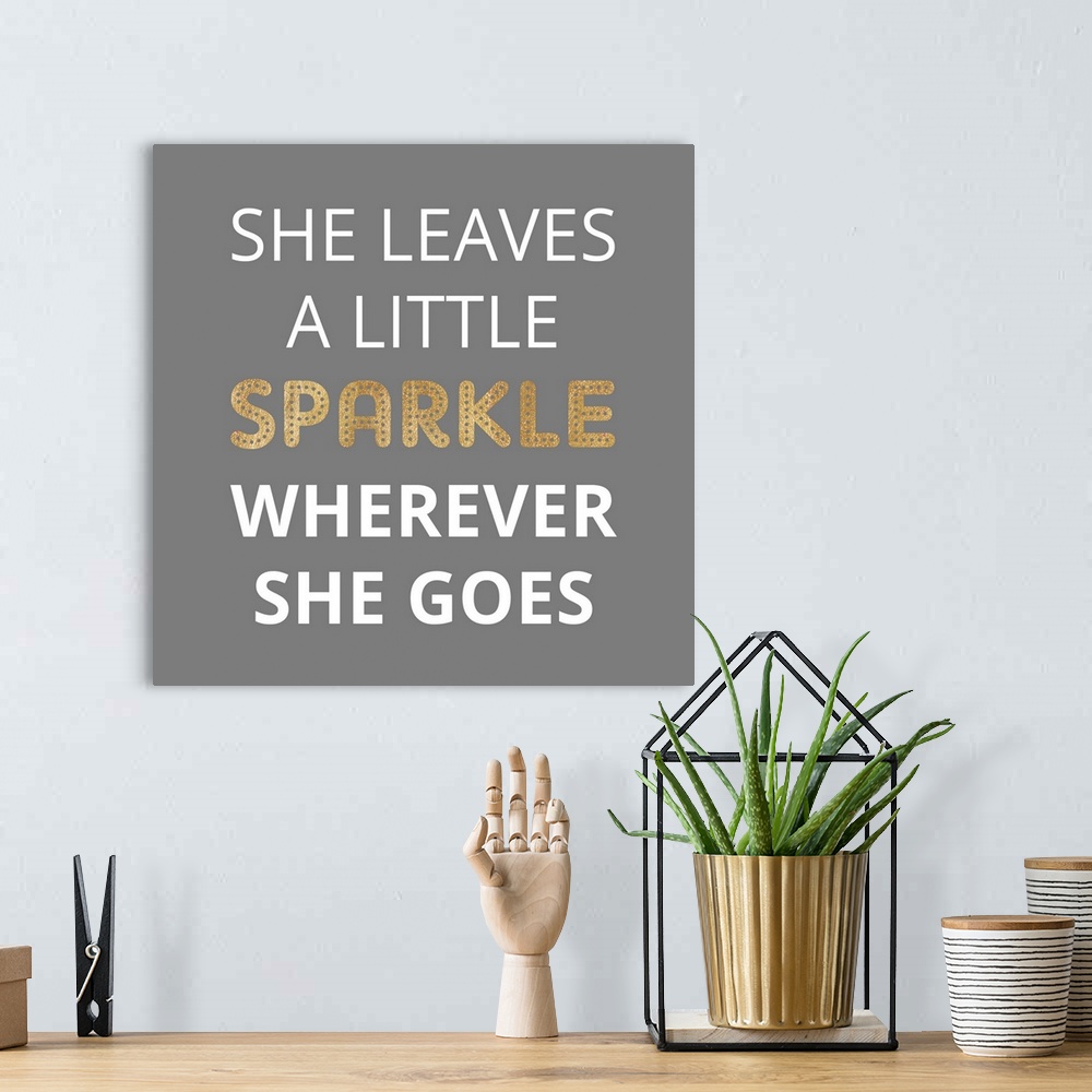 A bohemian room featuring Typography art reading "She leaves a little sparkle wherever she goes" in white and gold on grey.