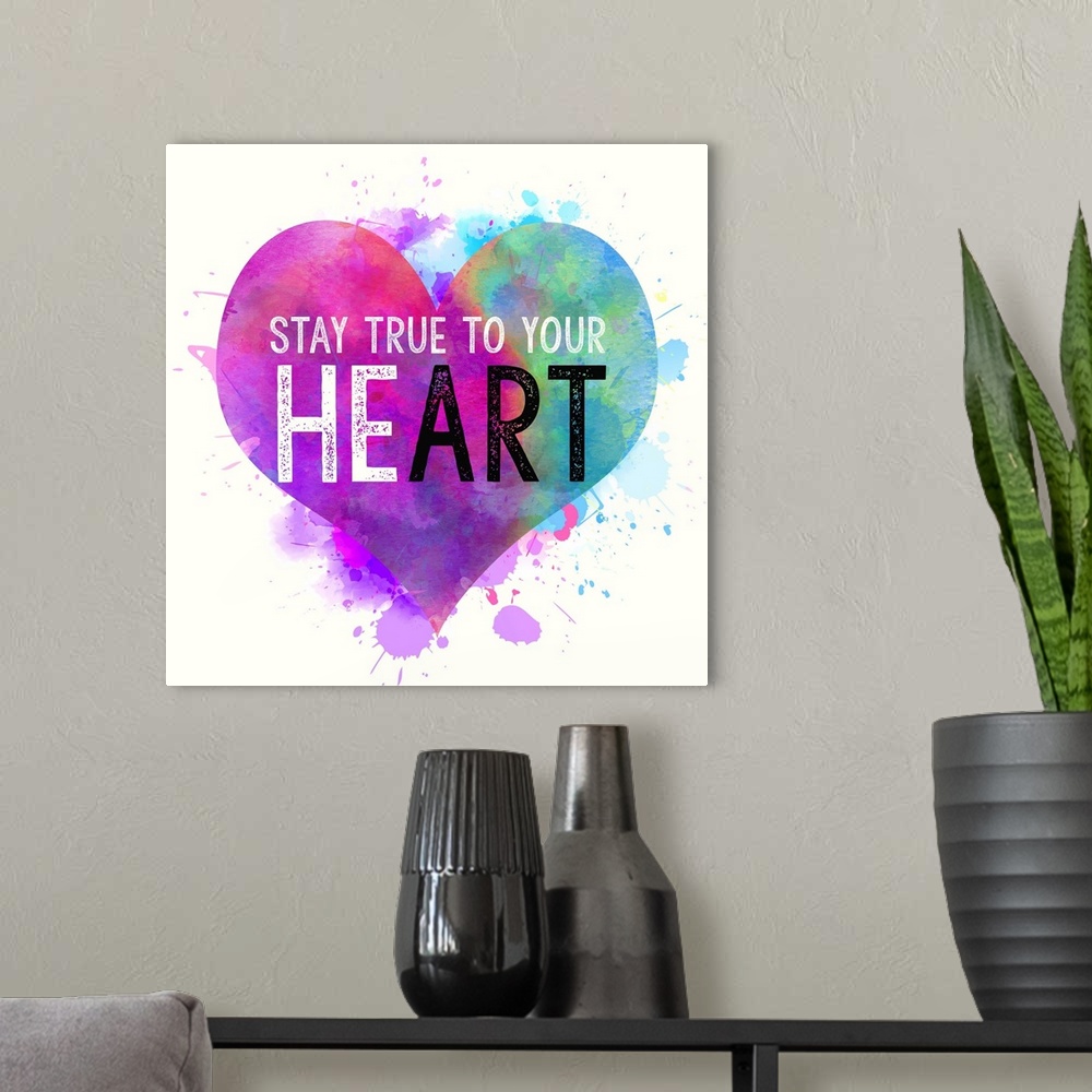 A modern room featuring "Stay True To Your Heart" written on top of a colorful, paint splattered heart.