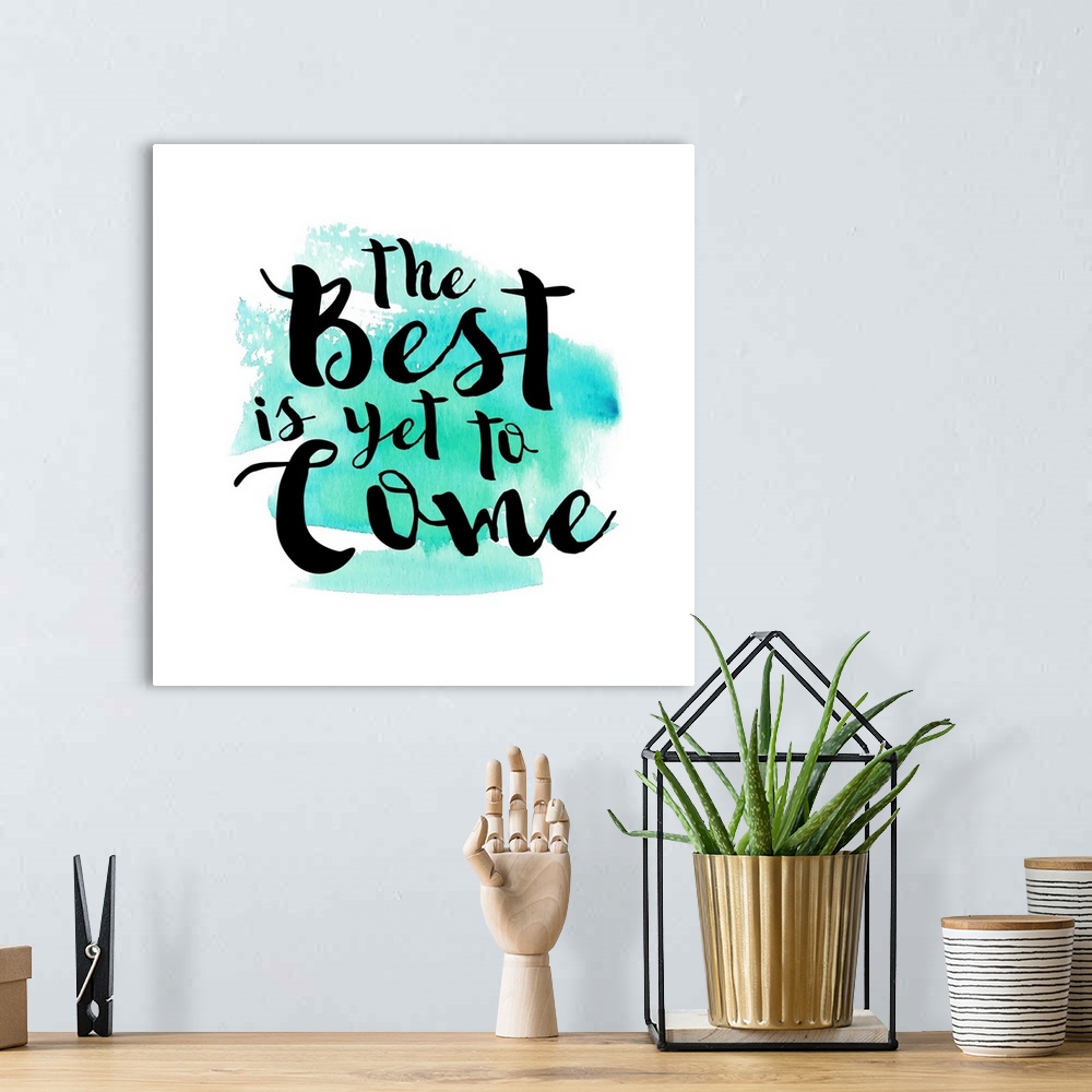 A bohemian room featuring Handlettered black text reading "The Best is yet to Come" over a teal watercolor wash.