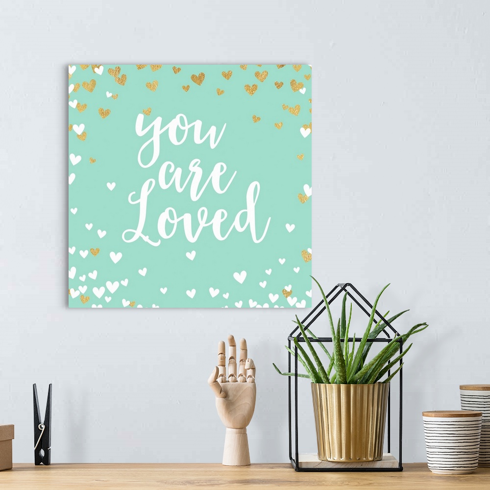 A bohemian room featuring "You are loved" in script text on turquoise with white and gold hearts.