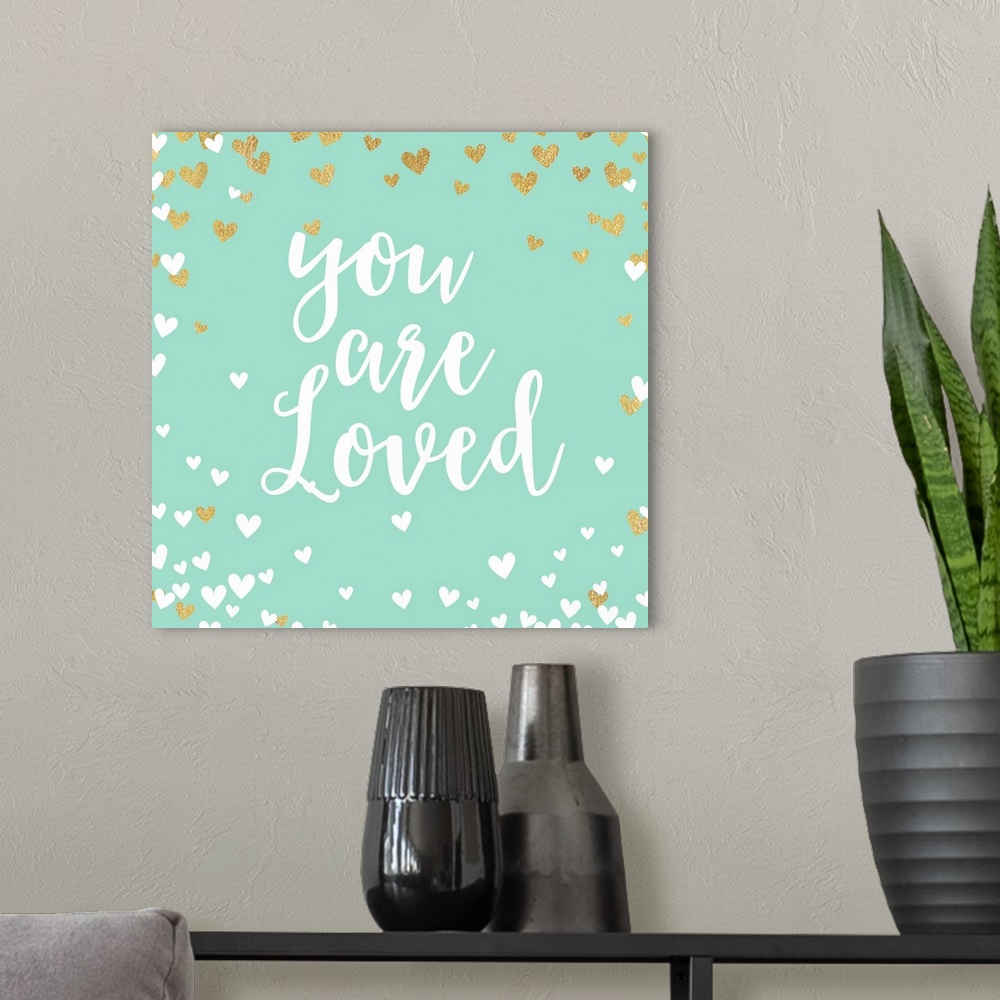 A modern room featuring "You are loved" in script text on turquoise with white and gold hearts.