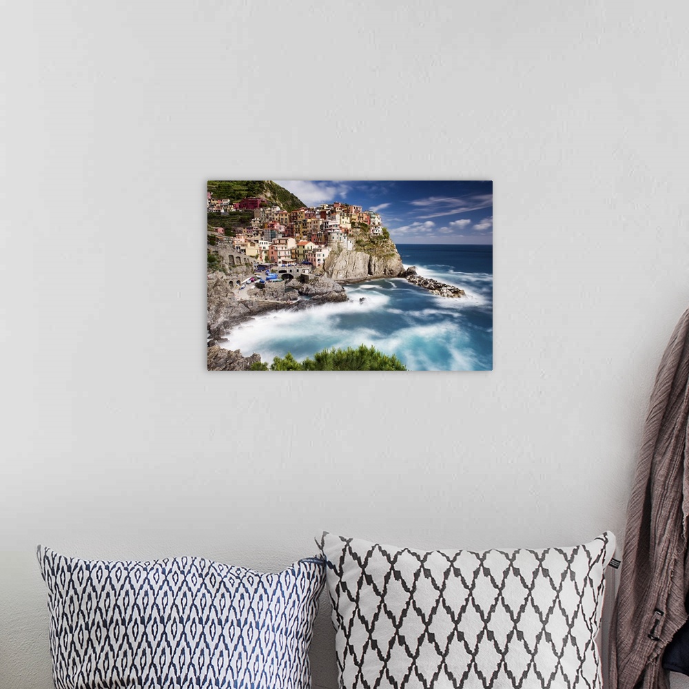 A bohemian room featuring A photograph of an Italian coastal village atop a cliff.