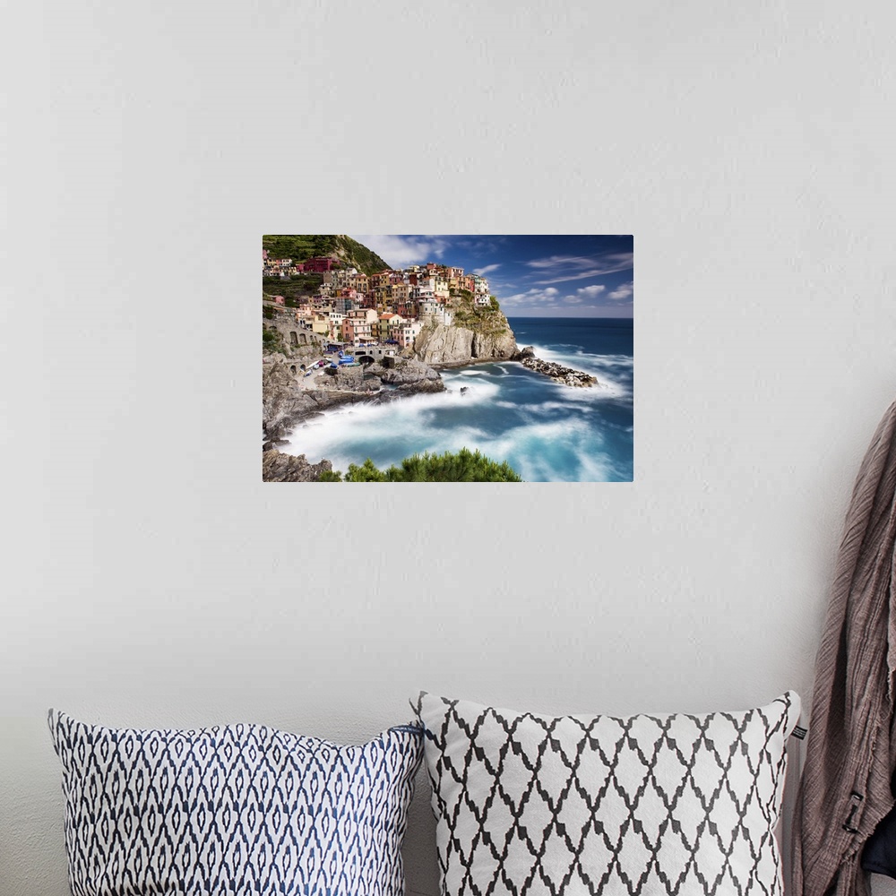 A bohemian room featuring A photograph of an Italian coastal village atop a cliff.