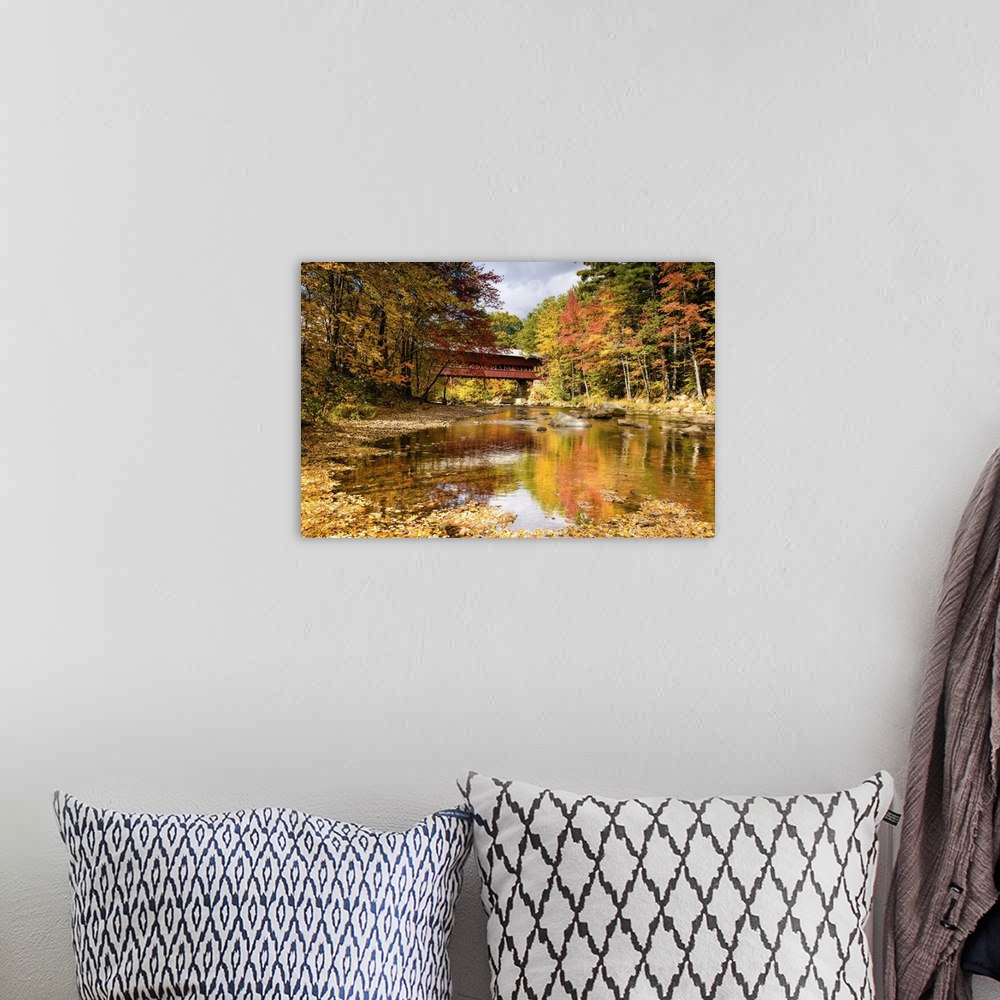 A bohemian room featuring A photograph of a covered bridge spanning a stream in a forest in autumn foliage.