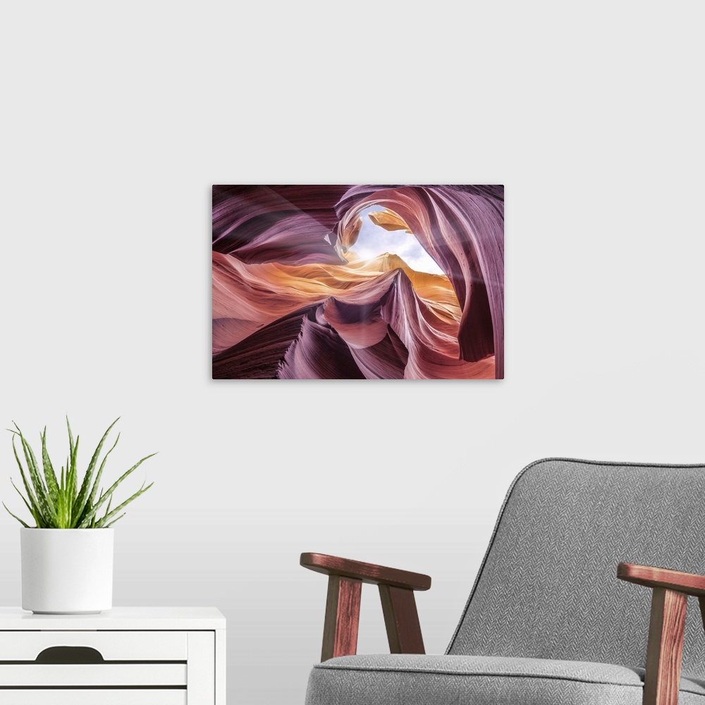 A modern room featuring An artistic photograph looking up at the opening of Antelope canyon with sunlight shining in.