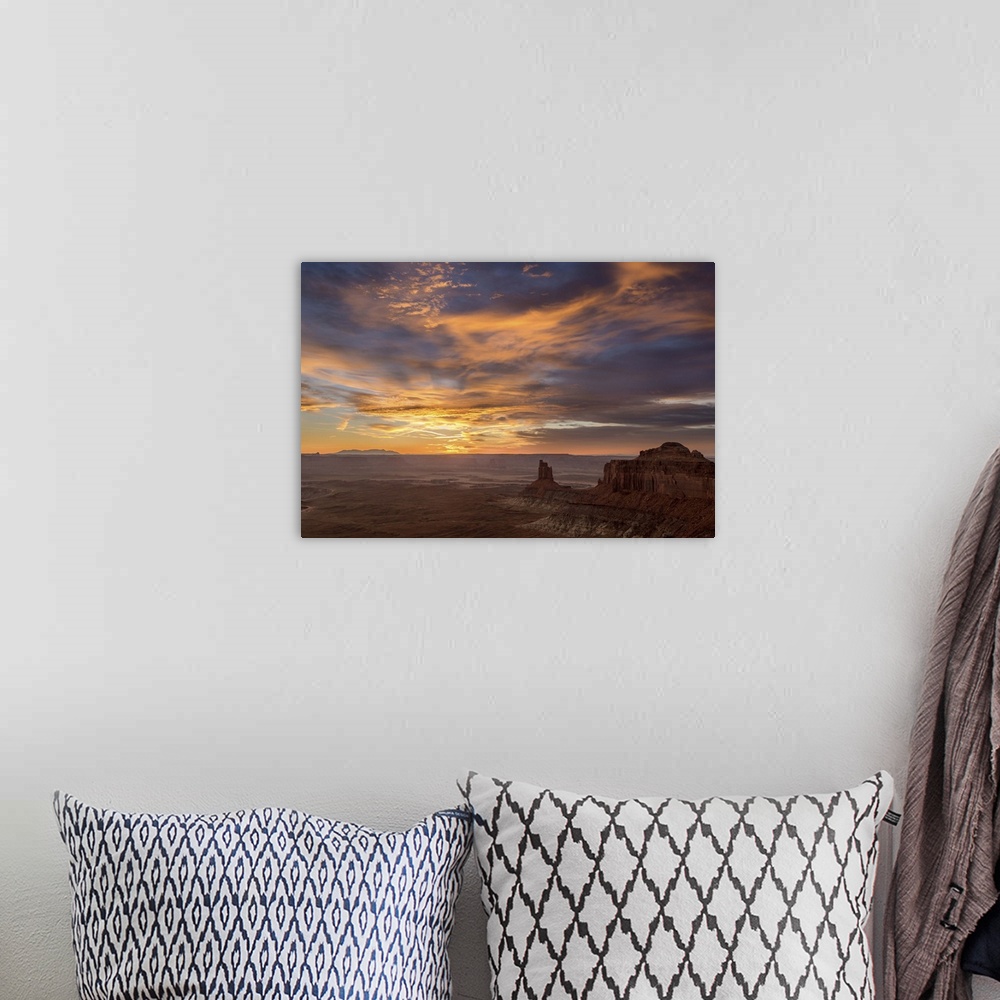 A bohemian room featuring A photograph of desert landscape illuminated by a warm sunset.