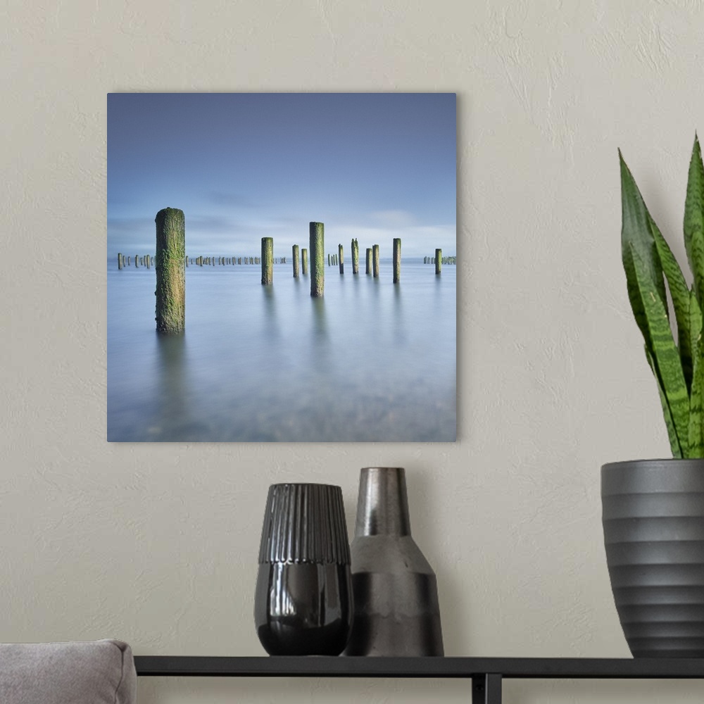 A modern room featuring A fine art photograph of pier posts standing in still calm water.