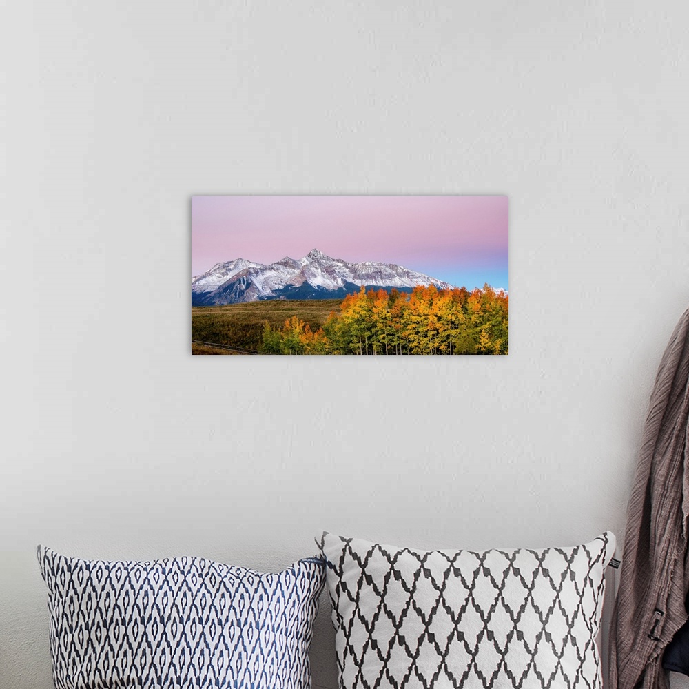 A bohemian room featuring Landscape photograph of a snowy mountain range with colorful Fall trees in the foreground and a c...