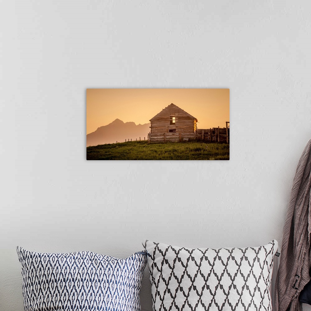 A bohemian room featuring Warm photograph of an old wooden barn on a hilltop with a silhouette of mountains in the background.