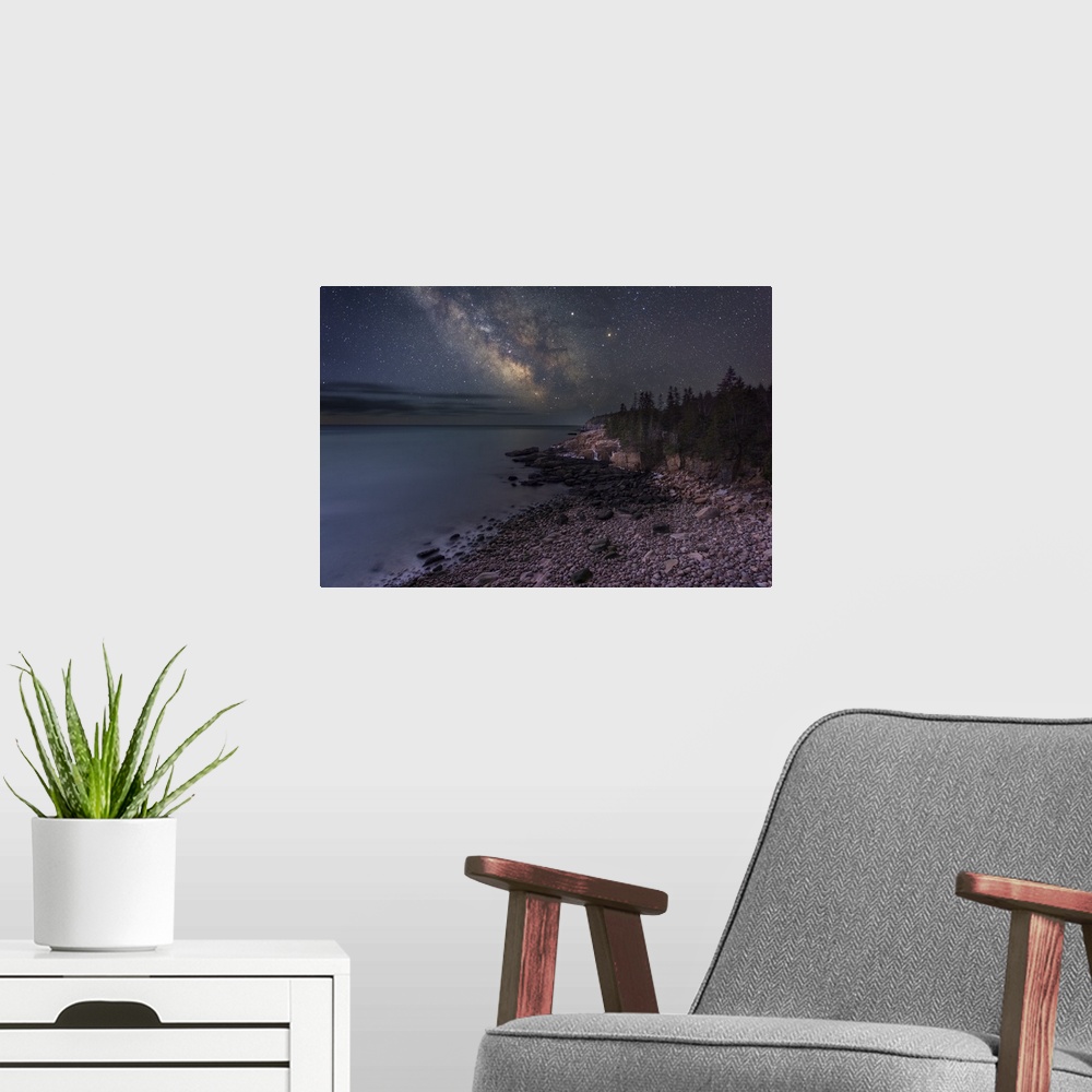 A modern room featuring A photograph of a rocky beach under a starry night sky.
