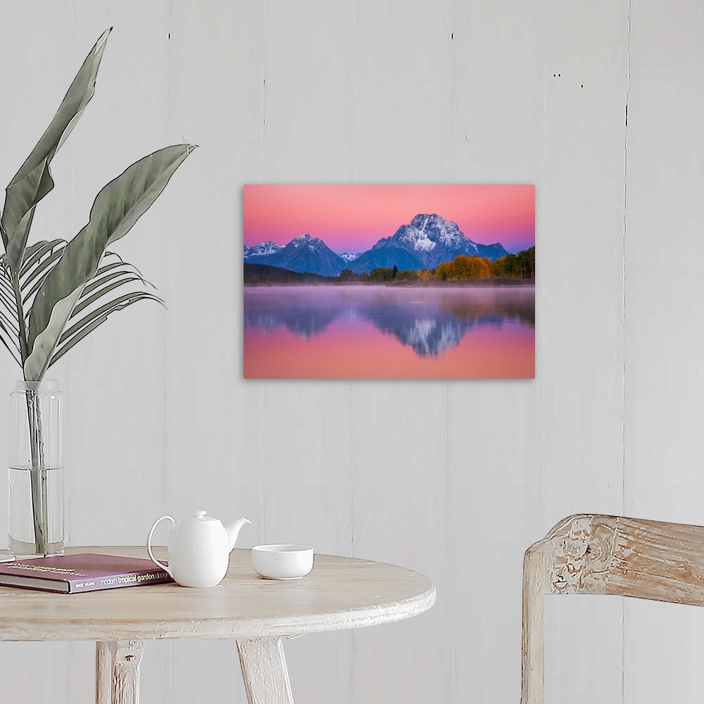 A farmhouse room featuring Snow-capped mountains under a pink sunset sky reflected in a lake.