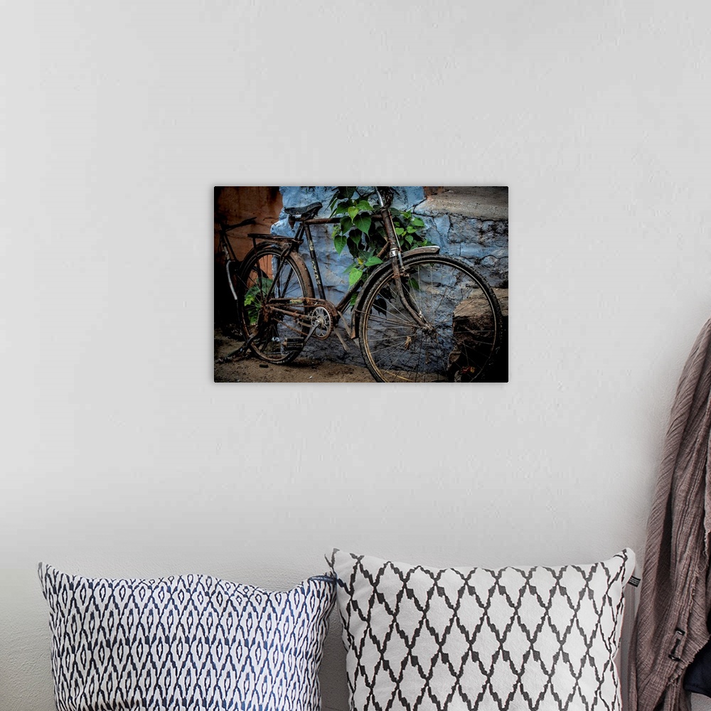 A bohemian room featuring Photograph of an old bicycle parked next to a bright blue wall.