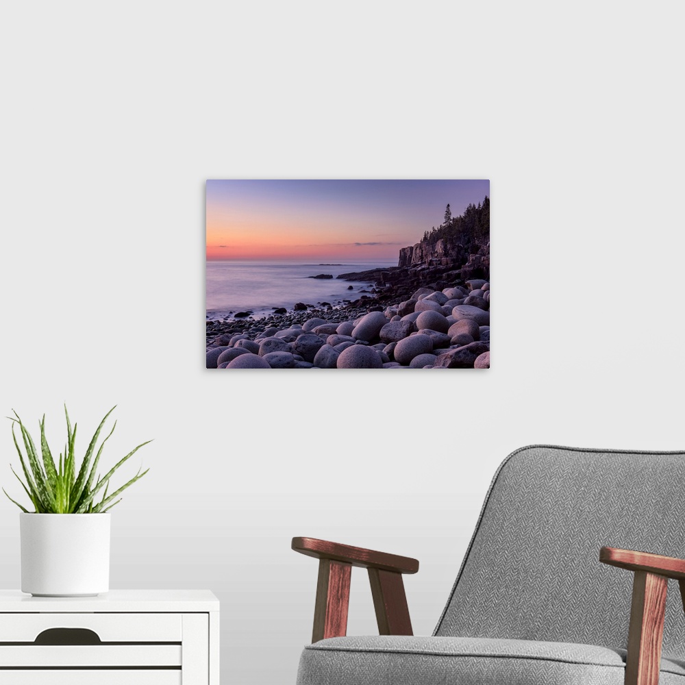 A modern room featuring Landscape photograph of a rocky beach shore with a warm sunrise.