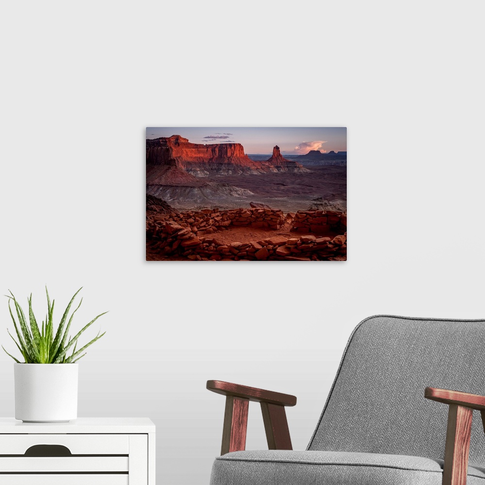 A modern room featuring Landscape photograph of stacked rocks creating a circle with canyons in the background at sunrise.