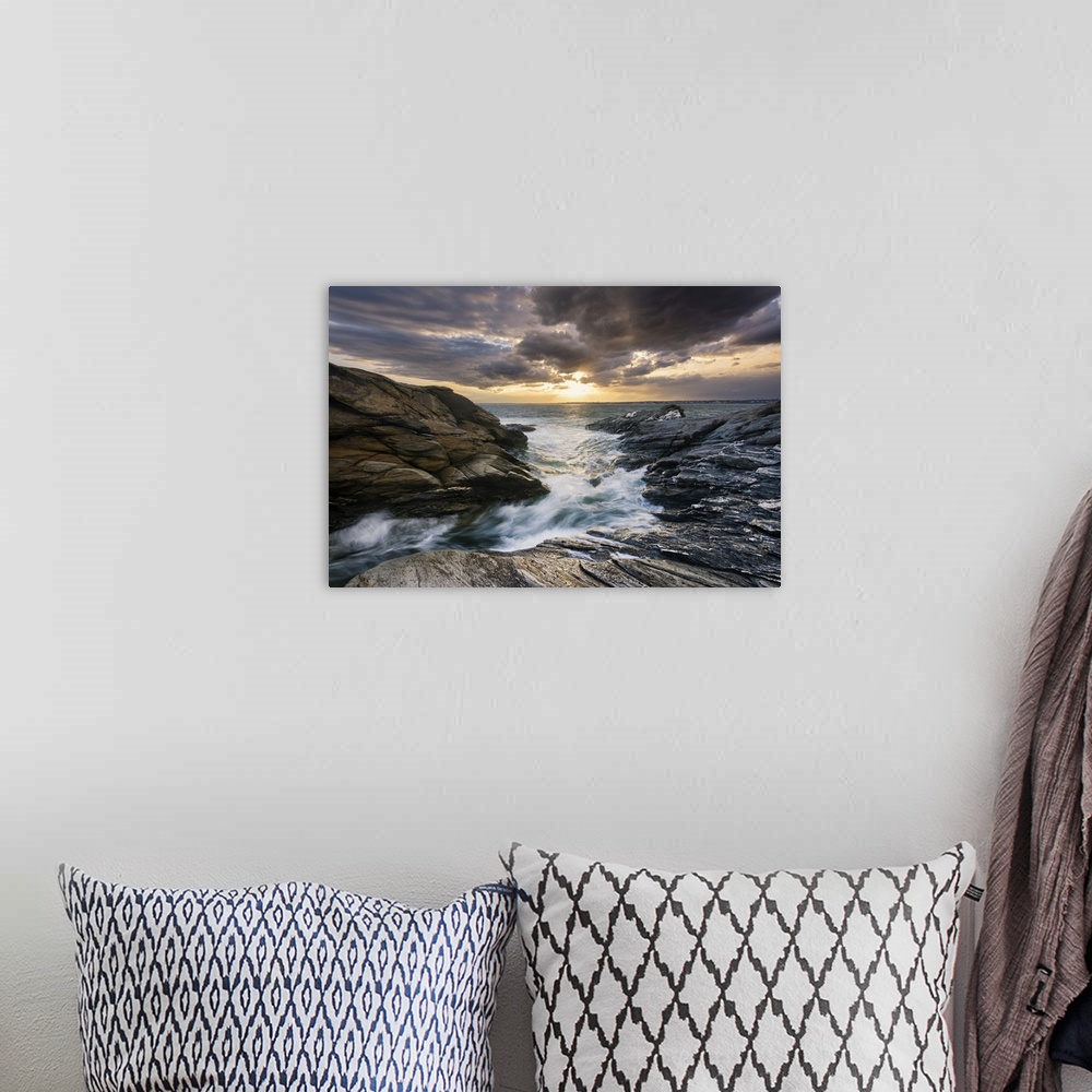 A bohemian room featuring Landscape photograph of a dramatic, cloudy sky over water rushing through a rocky path.