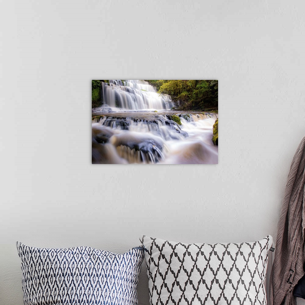 A bohemian room featuring Long exposure photograph of a rushing waterfall surrounded by lush green foliage.