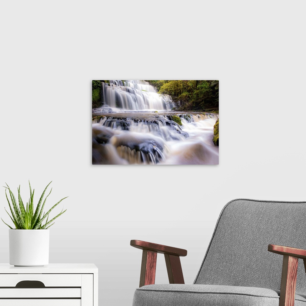 A modern room featuring Long exposure photograph of a rushing waterfall surrounded by lush green foliage.