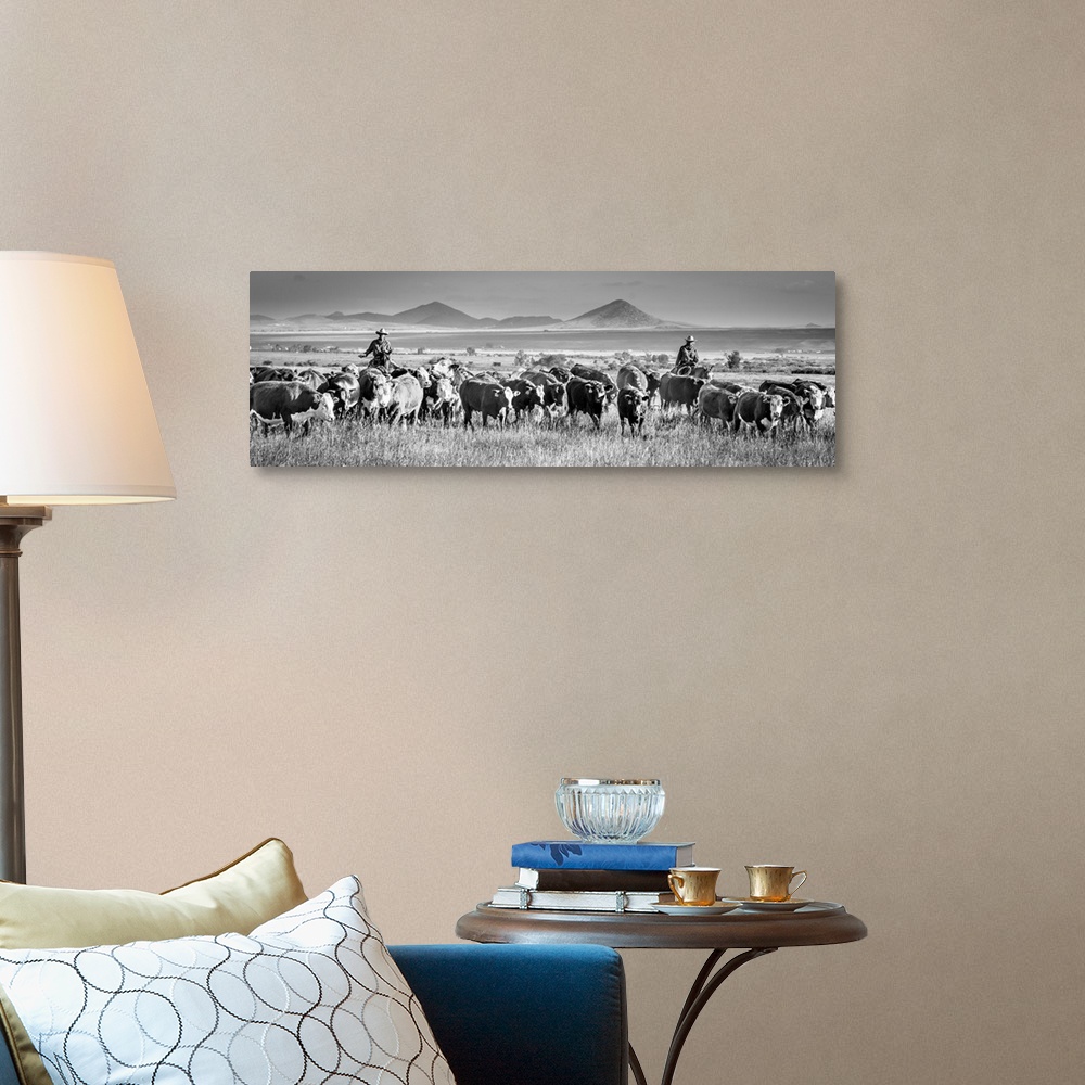 A traditional room featuring Black and white panoramic photograph of two cowboys herding cattle.