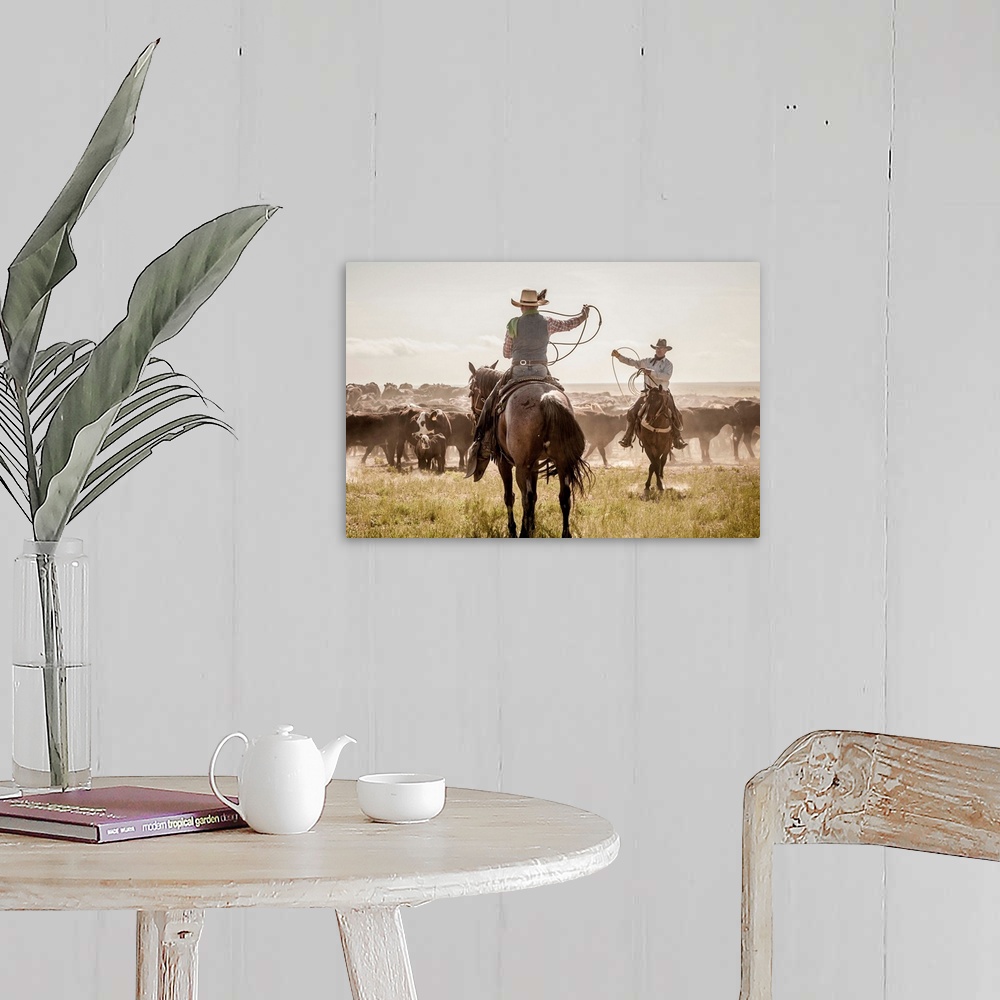 A farmhouse room featuring Photograph of two cowboys with their lassos in the air while herding cattle.