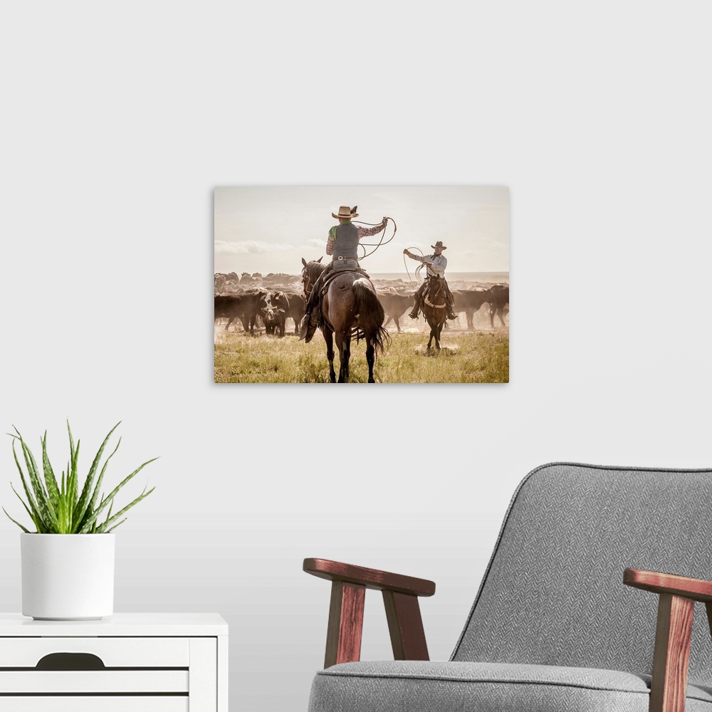A modern room featuring Photograph of two cowboys with their lassos in the air while herding cattle.