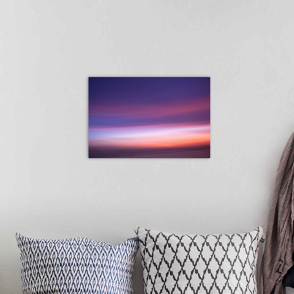A bohemian room featuring An artistic abstract photograph of a light purple and pink motion blurred cloudscape.