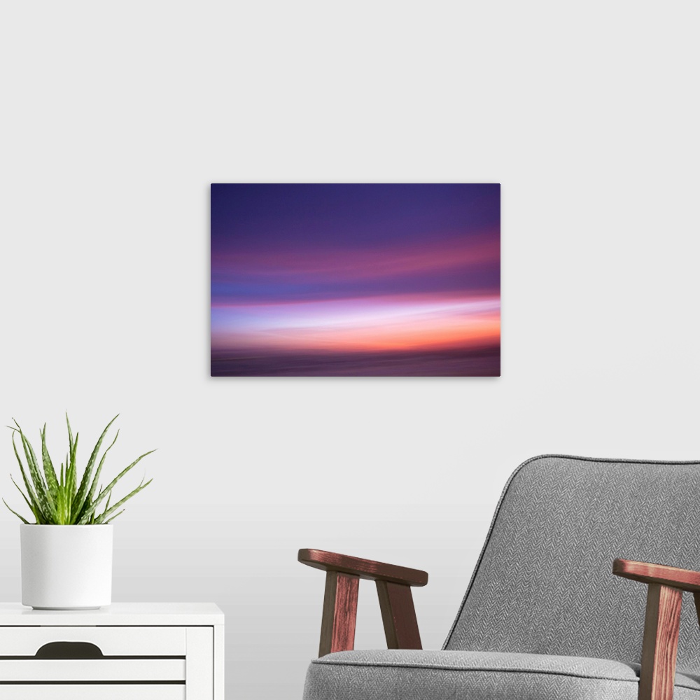 A modern room featuring An artistic abstract photograph of a light purple and pink motion blurred cloudscape.